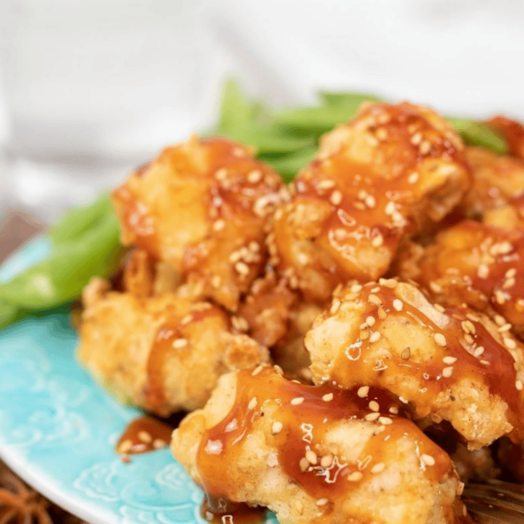 Bowl of copycat McDonald's sweet and sour sauce with a chicken nugget being dipped in.