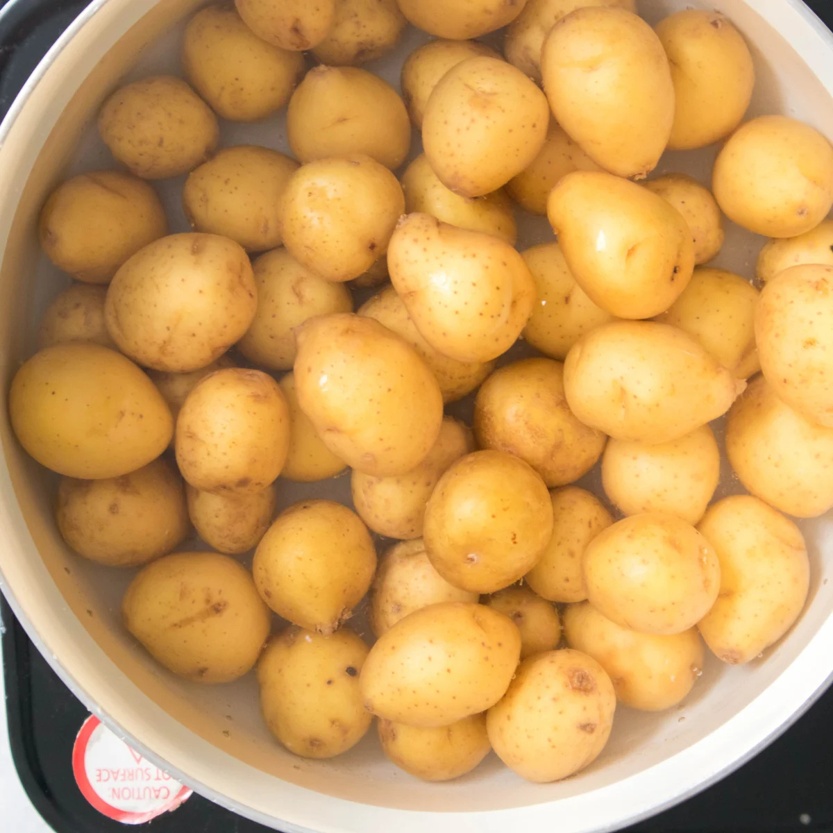 Boiling potatoes in salted water until fork-tender in a large pot.