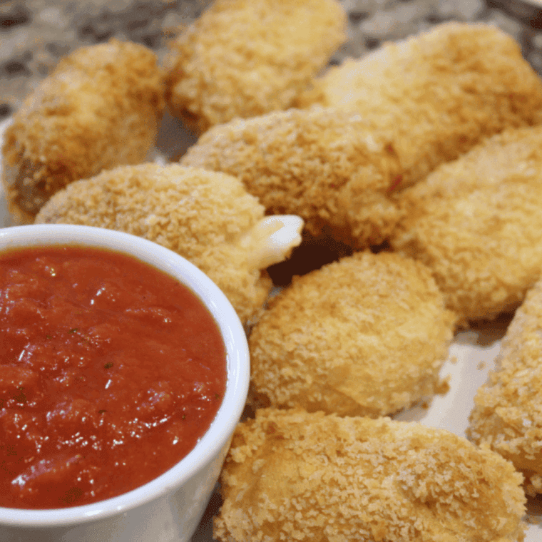 Golden, crispy Air Fryer Brie Bites with melted brie inside, served on a plate.