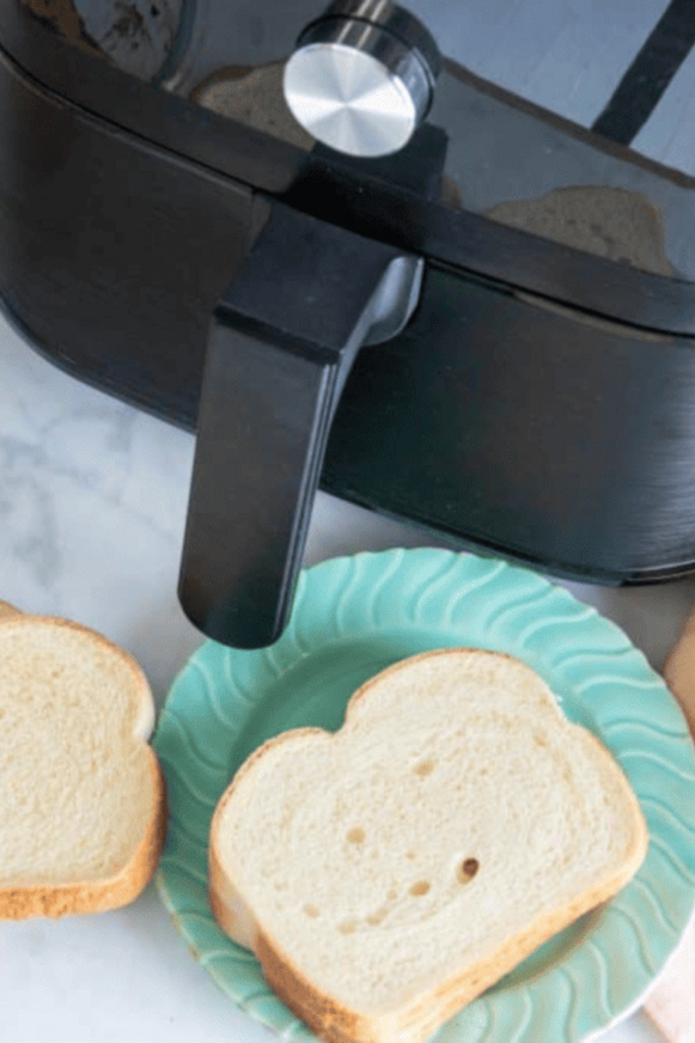 Piece of bread ready for soaking near air fryer basket.