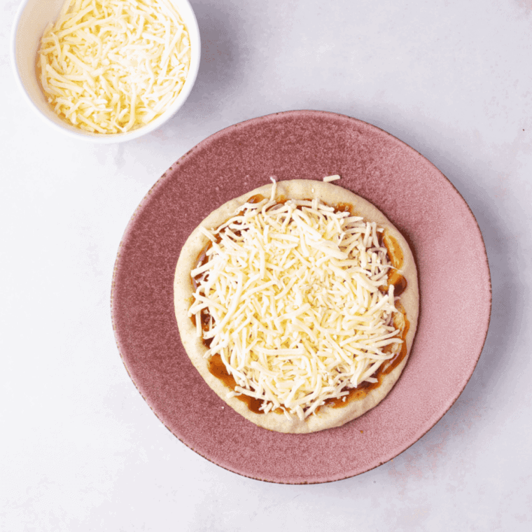 Spread seasoned tomato sauce over pita bread and top with shredded mozzarella cheese for a delicious base.