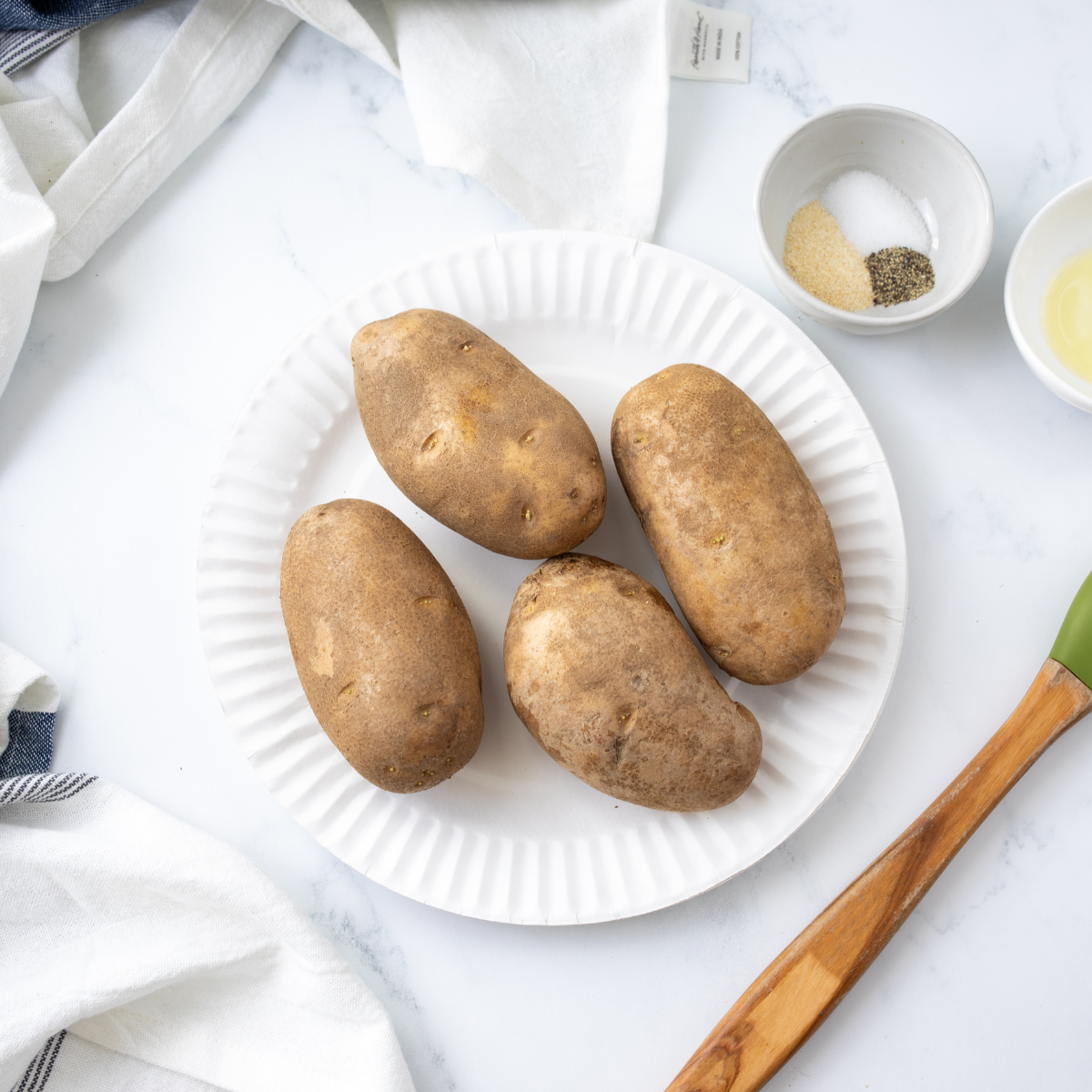 Russet potatoes washed, scrubbed, dried, and coated with olive oil and salt.