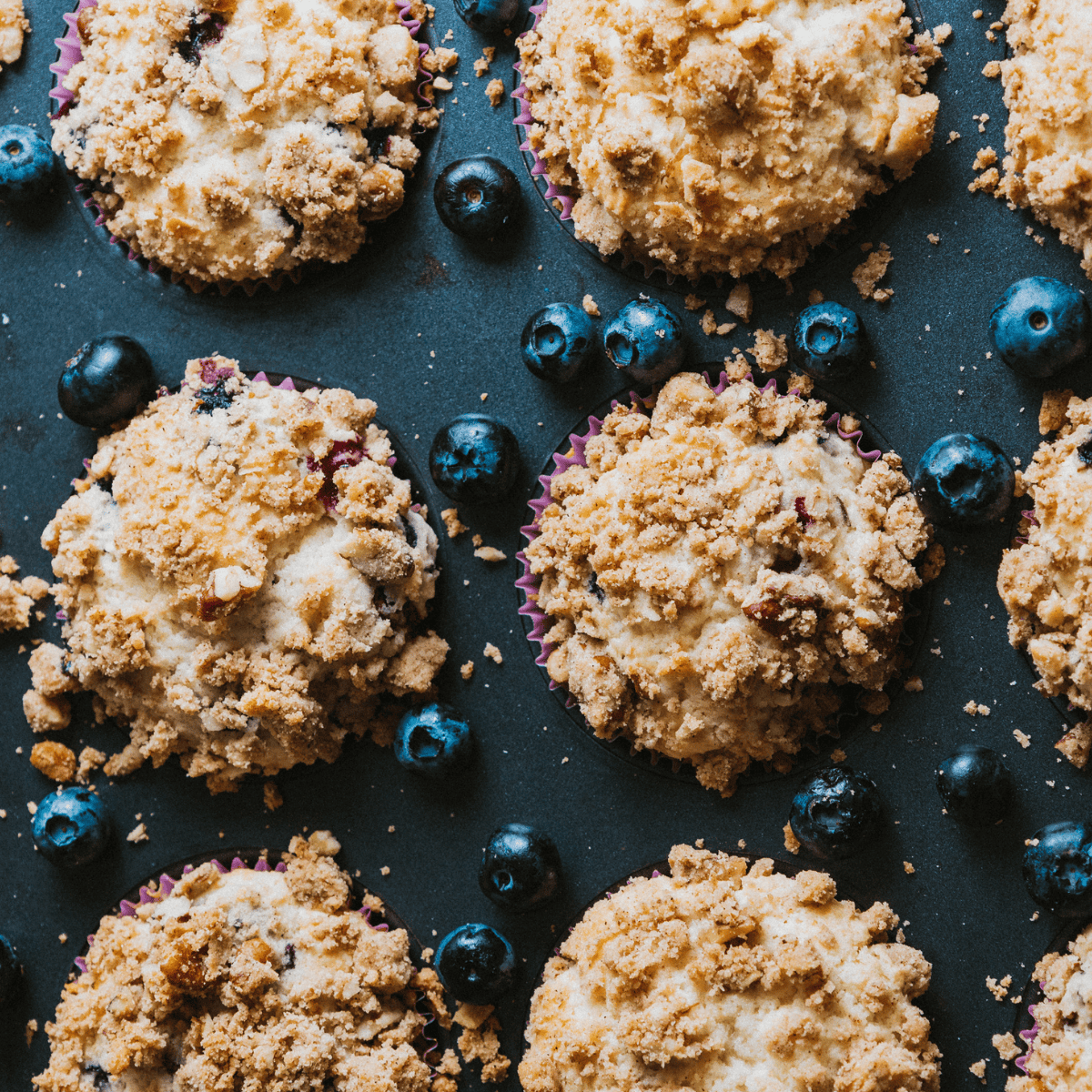 Freshly baked Ninja Woodfire Blueberry Muffins with golden crumble topping on a cooling rack, ready to serve.