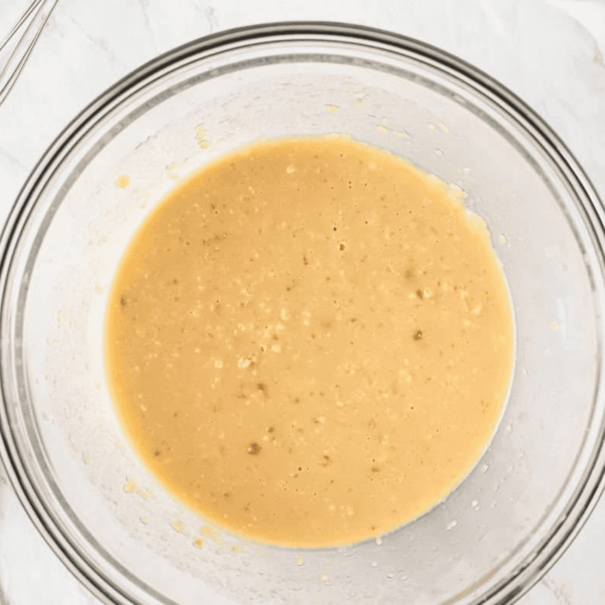 Whisking eggs, milk, and applesauce in a bowl for protein donut batter