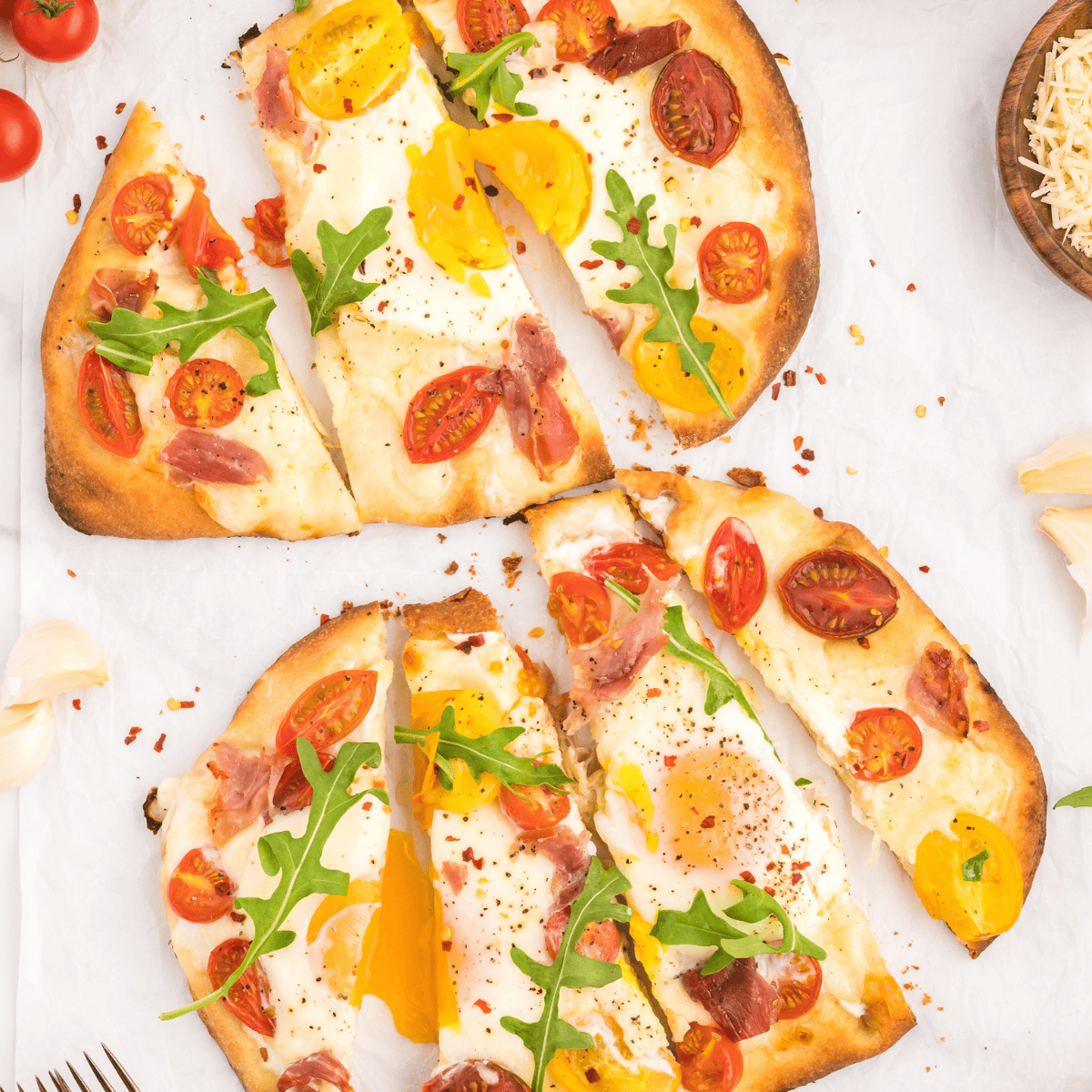Air Fryer Breakfast Flatbread Pizza with melted cheese, eggs, prosciutto, and cherry tomatoes.