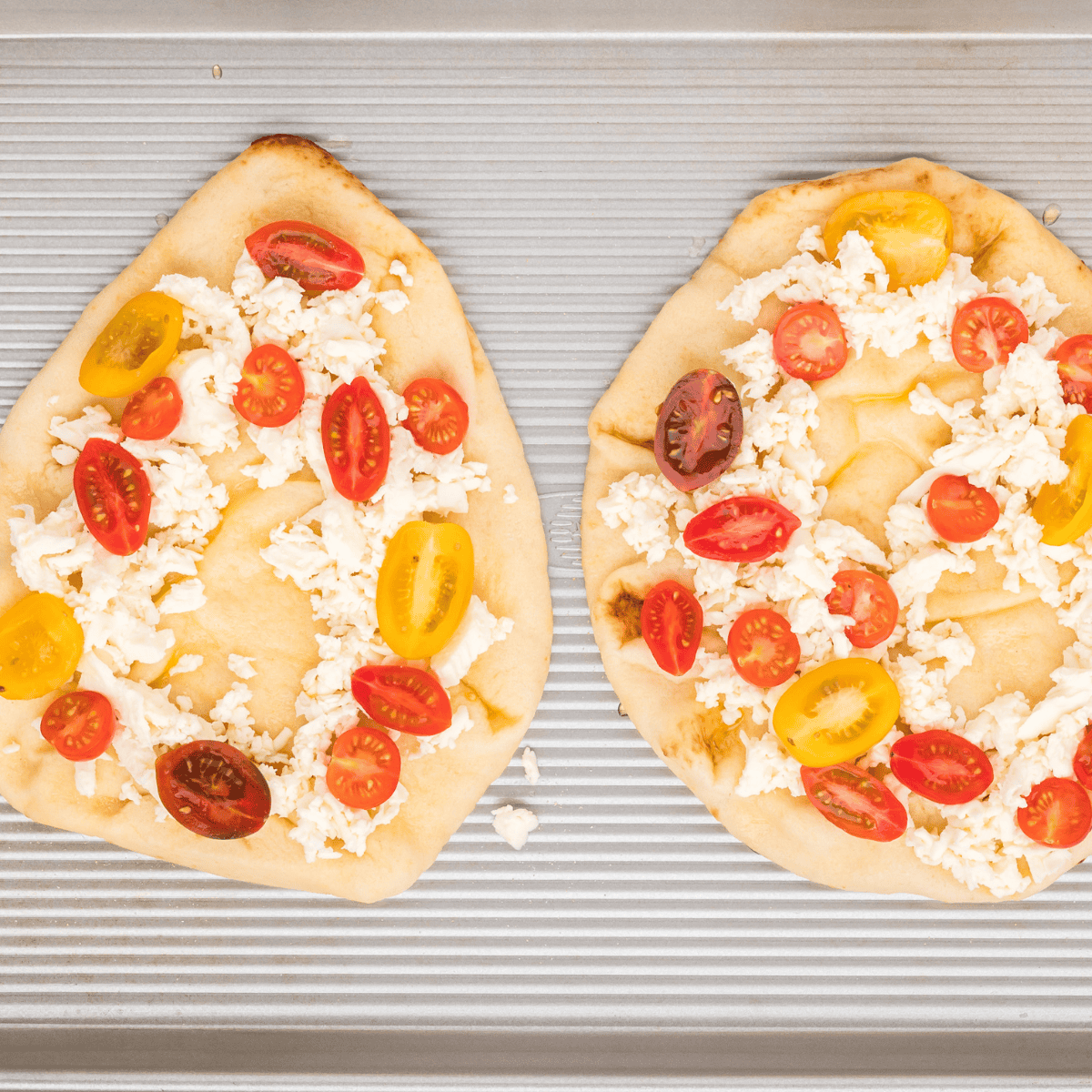 Cherry tomatoes halved and prosciutto pieces arranged on flatbread.