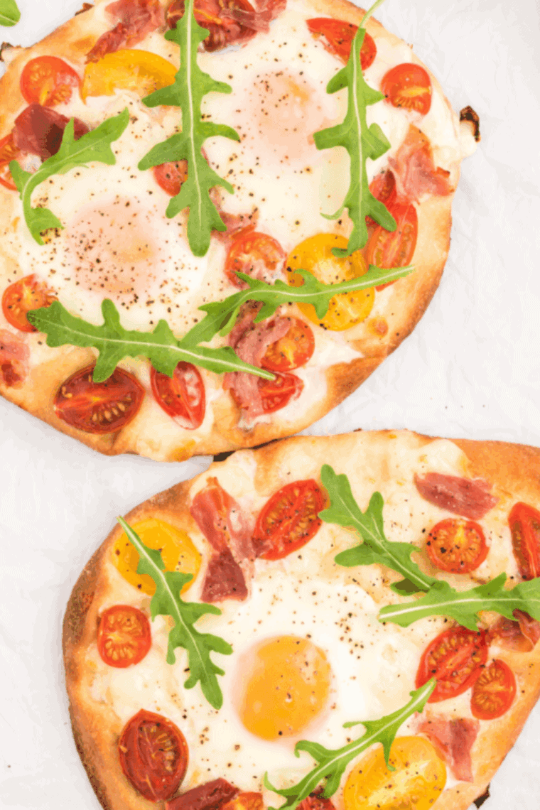 Air fryer breakfast flatbread pizza topped with egg, prosciutto, cherry tomatoes, and cheese, ready to serve