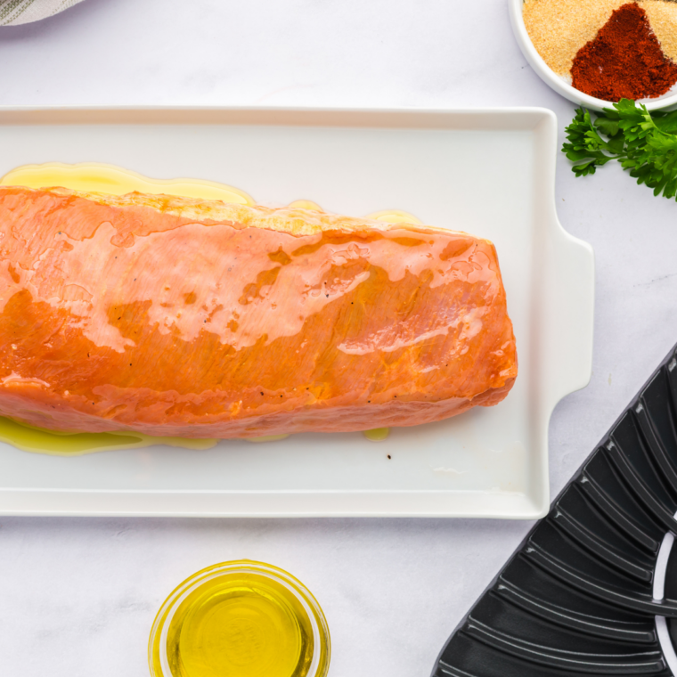 Frozen pork tenderloin brushed with oil and coated in seasonings.