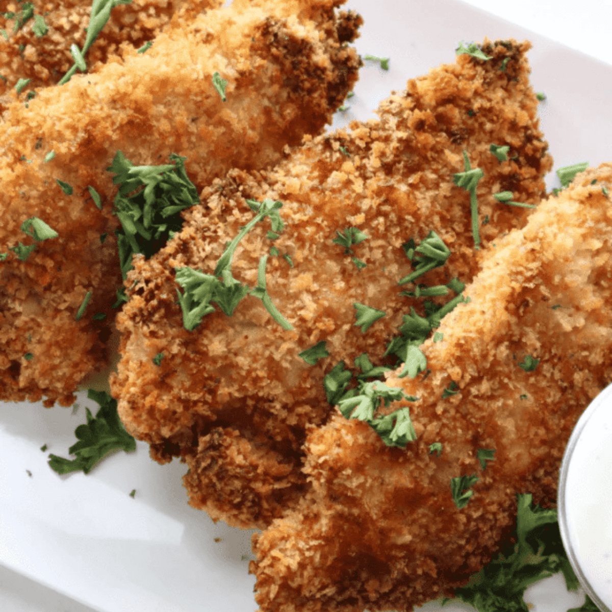 Stack of golden air fryer lemon pepper chicken tenders garnished with parsley