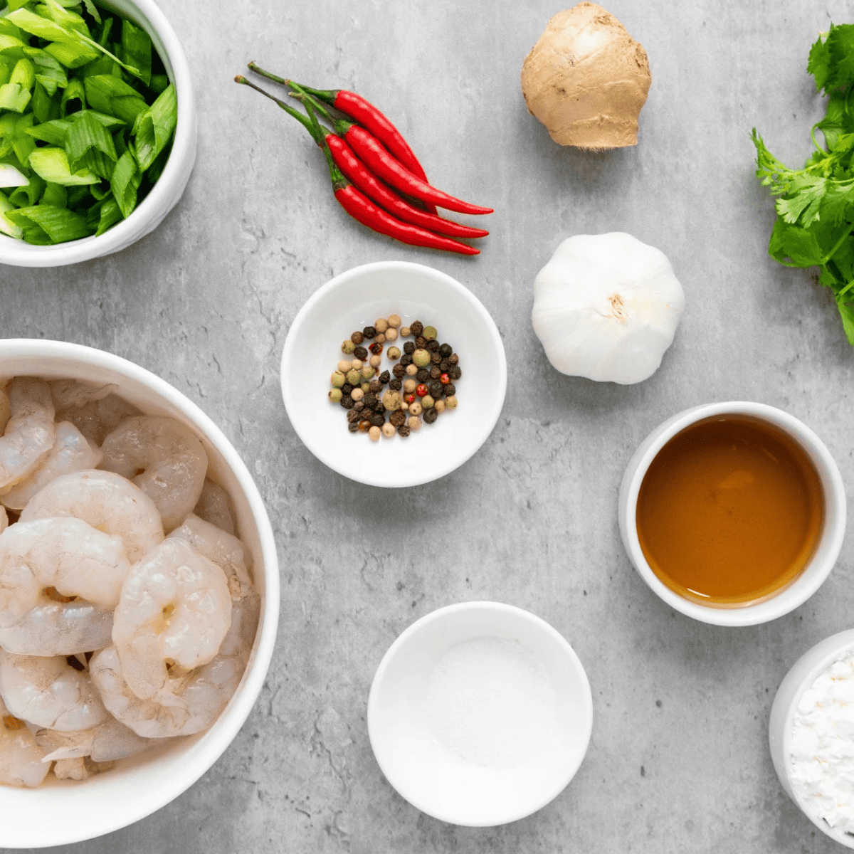 :
Ingredients for air fryer salt and pepper shrimp on a marble countertop: raw shrimp, cornstarch, white pepper, garlic cloves, red chili, and scallions