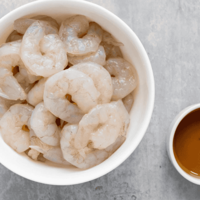 Raw shrimp being patted dry with paper towels before coating
