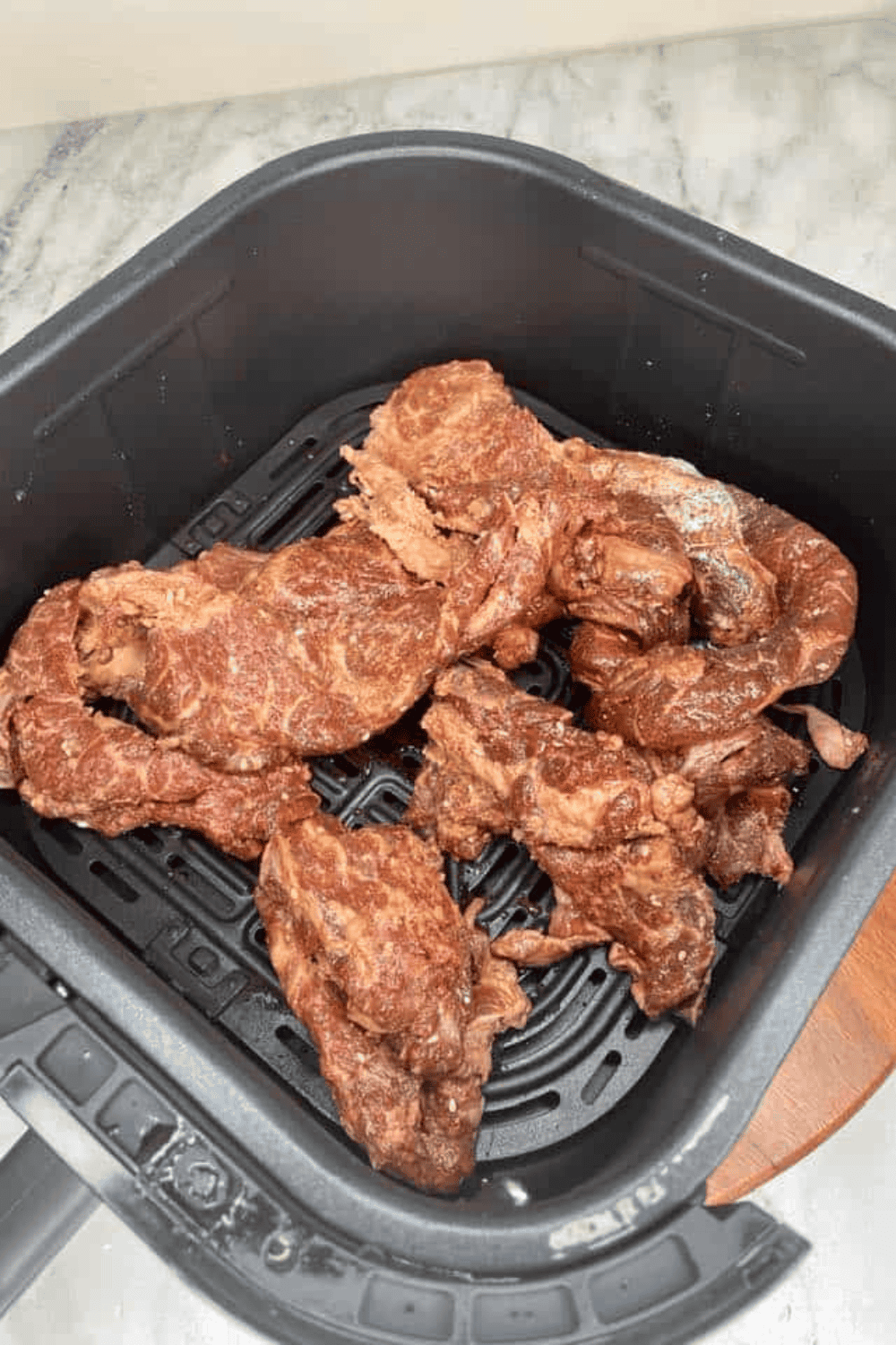 Marinated Bool Kogi beef slices arranged in a single layer in an air fryer basket