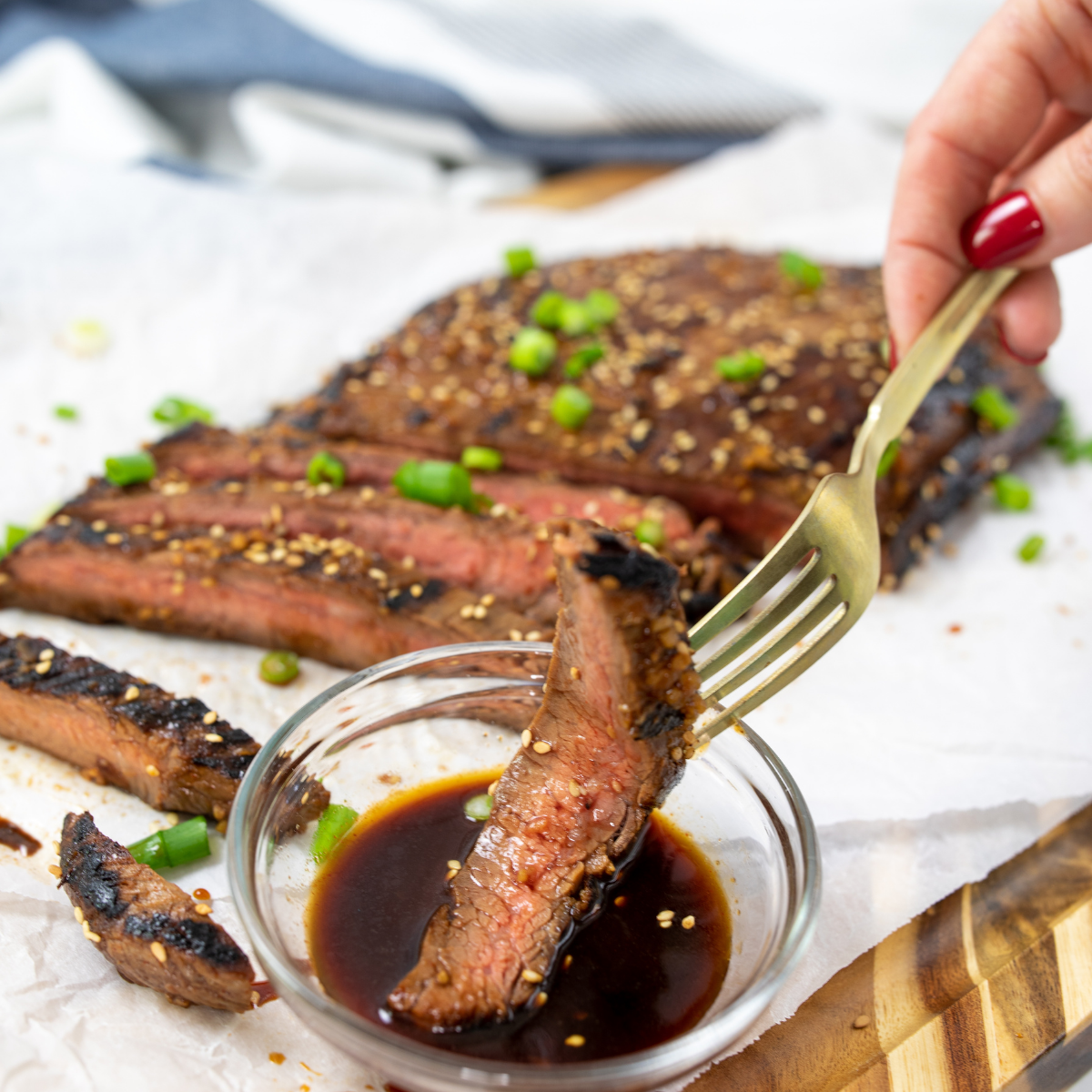 Flank steak sizzling on a hot Blackstone griddle with visible sear marks and smoke rising.