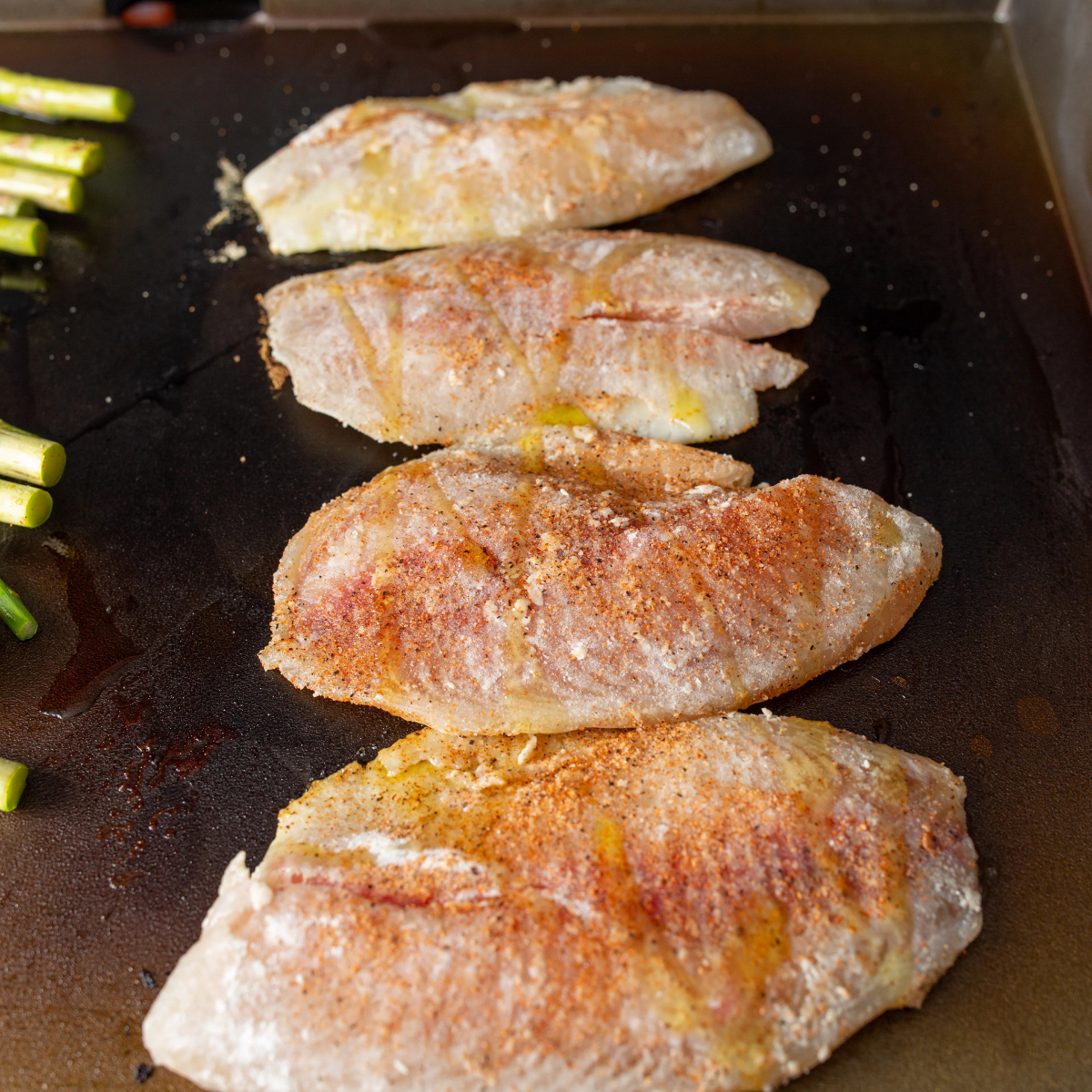 Tilapia fillets being patted dry and coated with oil and seasoning before cooking.
