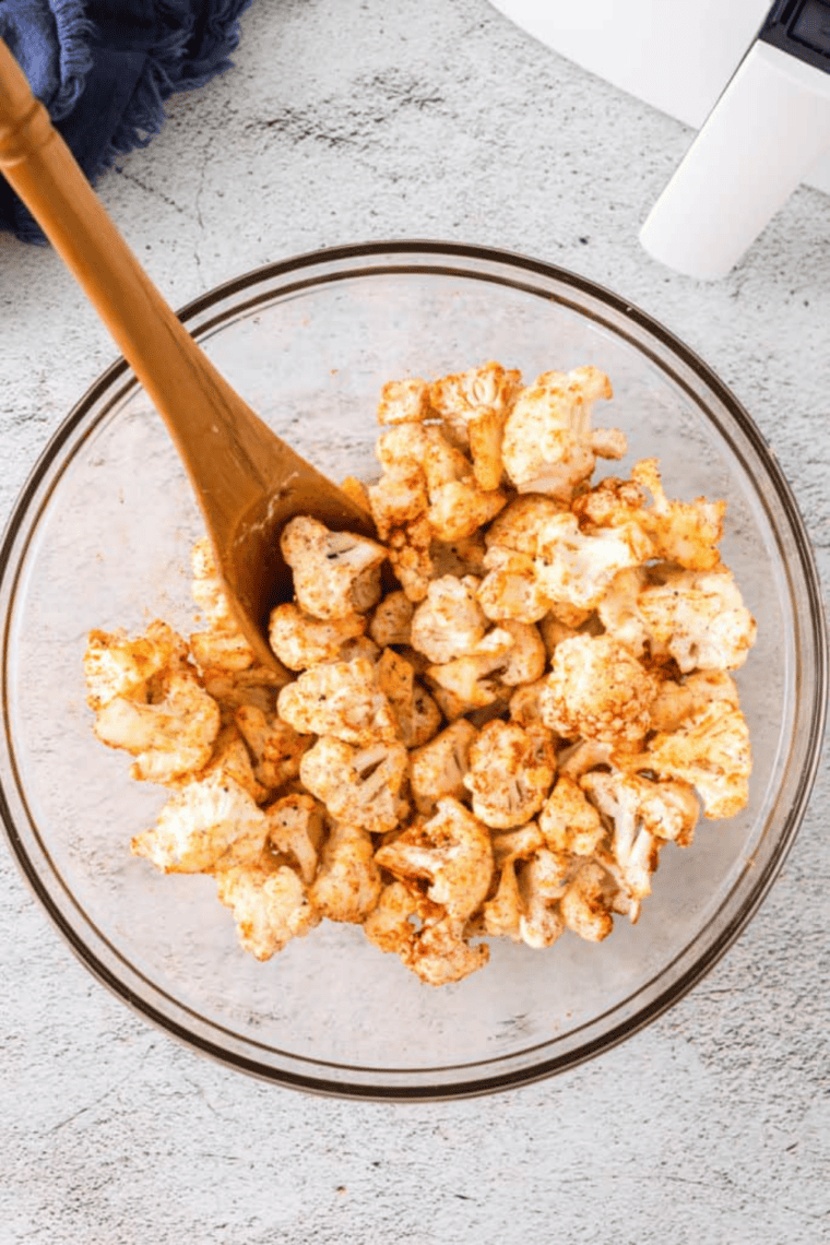Cauliflower florets spread on a baking sheet, roasted to golden brown, topped with optional Parmesan cheese and chopped parsley, ready to serve.