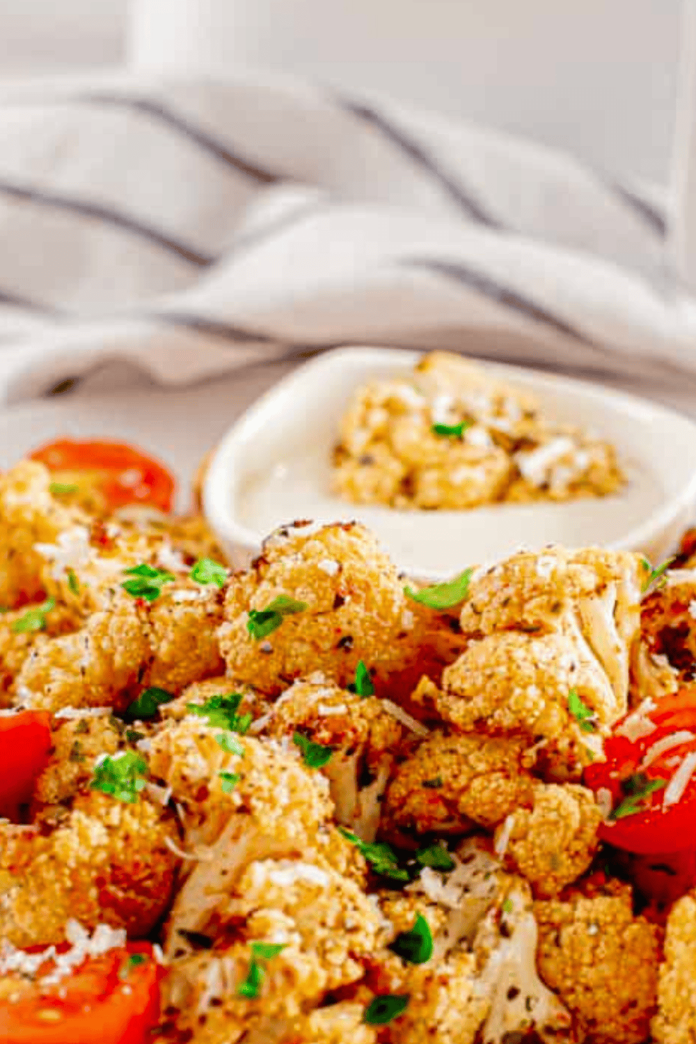 Golden roasted cauliflower florets tossed with garlic, olive oil, and optional Parmesan on a white serving plate.