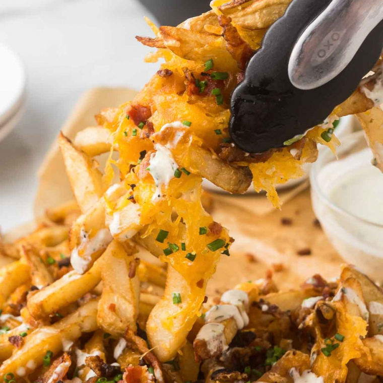 Crumbled bacon and fried jalapeños scattered over queso-covered steak fries