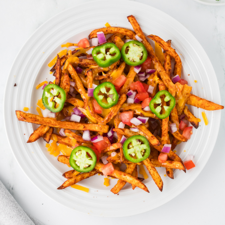 Crumbled bacon and fried jalapeños scattered over queso-covered steak fries