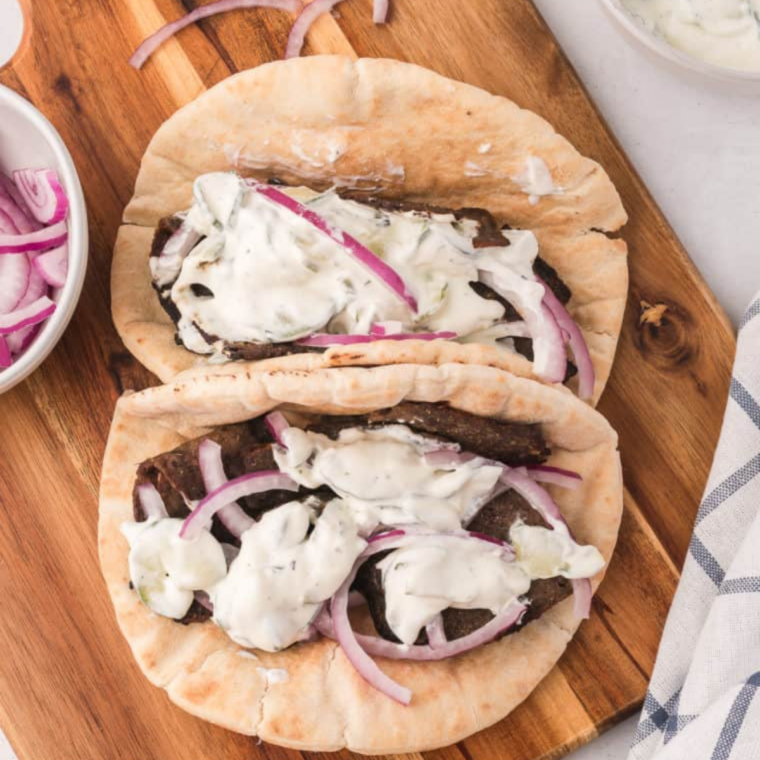 Gyro sandwich cut in half showing crisp air fried gyro meat and tzatziki inside the pita