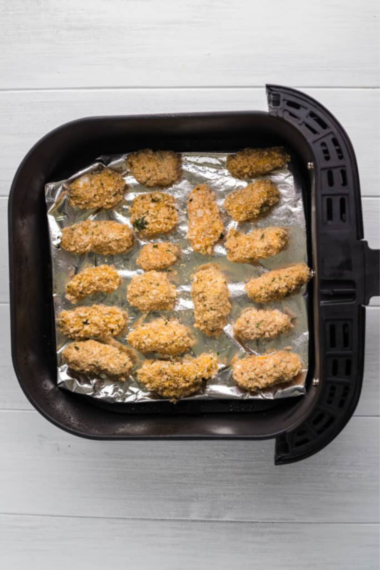 Breaded cheese curds arranged in a single layer in the air fryer basket