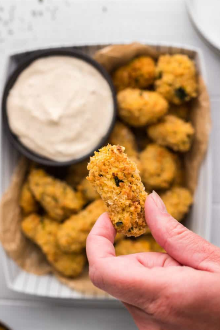 Crispy air fryer cheese curds on a paper-towel-lined plate, one broken open to show melted cheese