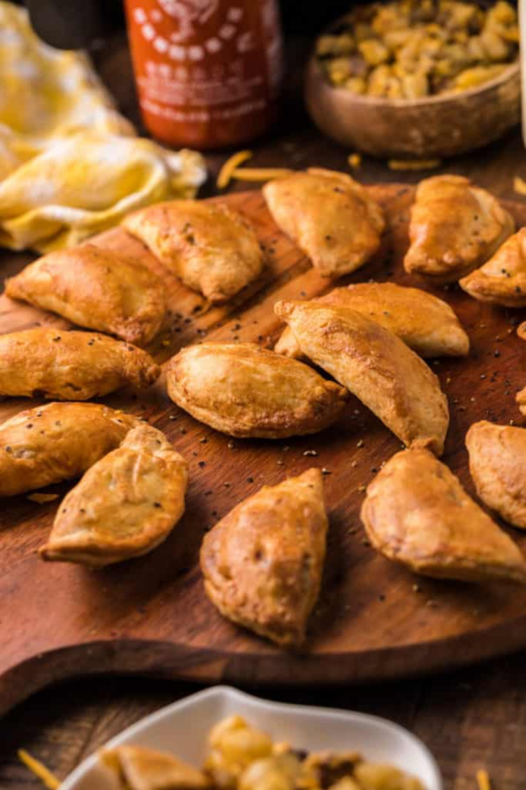 Air fryer empanada broken open showing beef filling next to dipping sauce