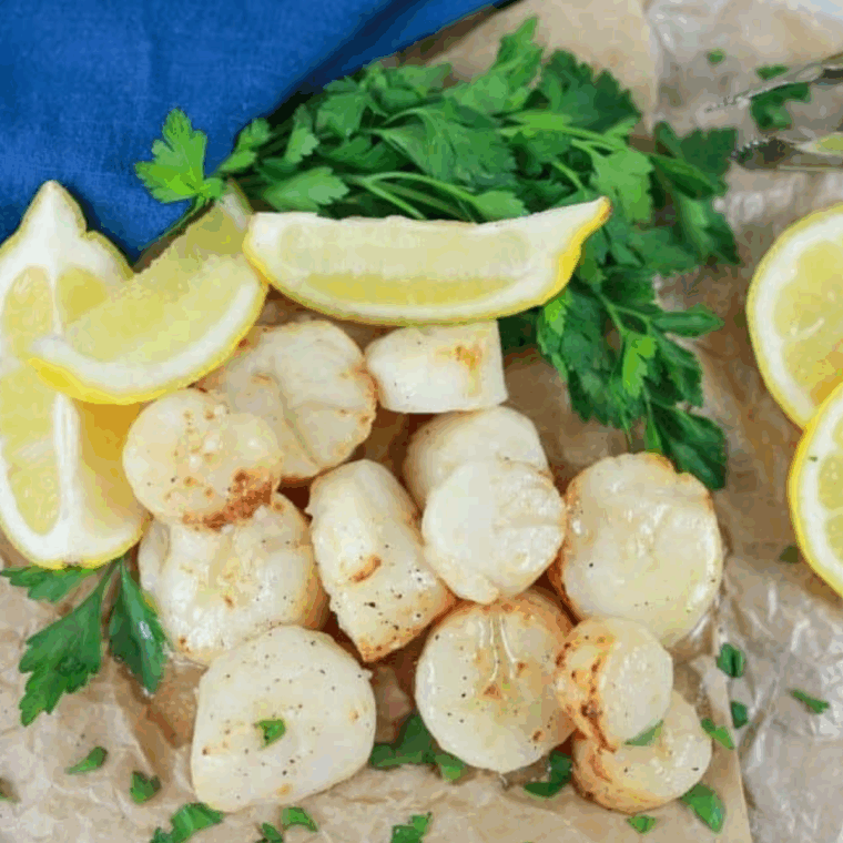Golden, perfectly cooked air fryer frozen scallops served with lemon wedges.