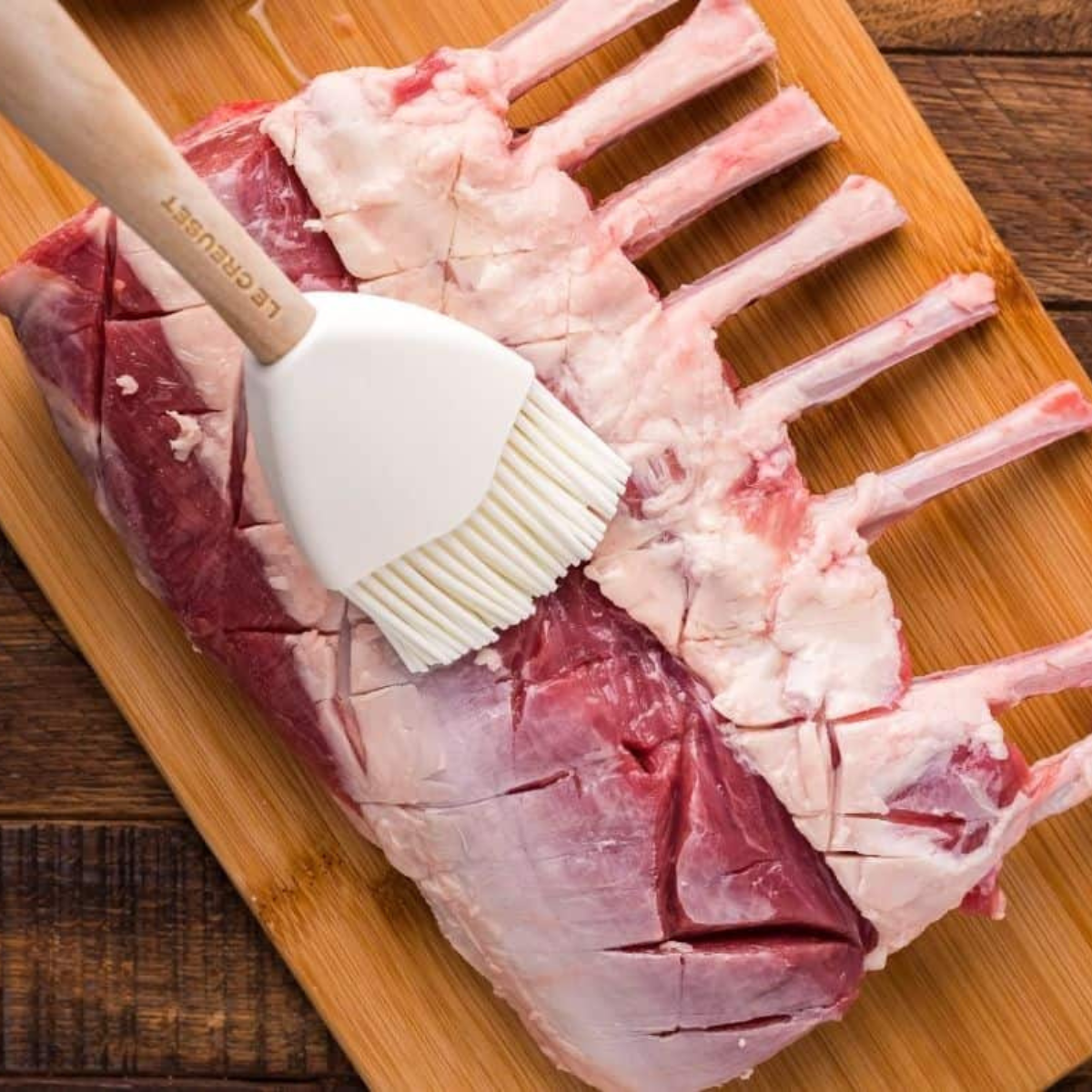 Olive oil, garlic powder, rosemary, and thyme brushed over raw lamb cutlets