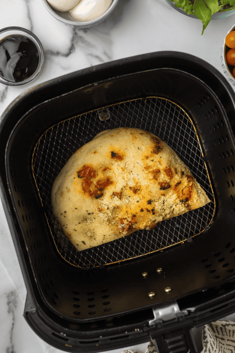 Toasted focaccia topped with burrata, arugula, and fresh tomatoes after air frying