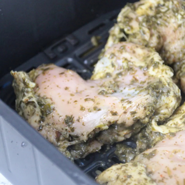 Raw marinated chicken thighs arranged in a single layer in an air fryer basket