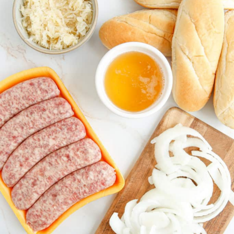 ingredients for Blackstone brats: uncooked bratwurst, bell peppers, sliced onion, buns, and condiments.