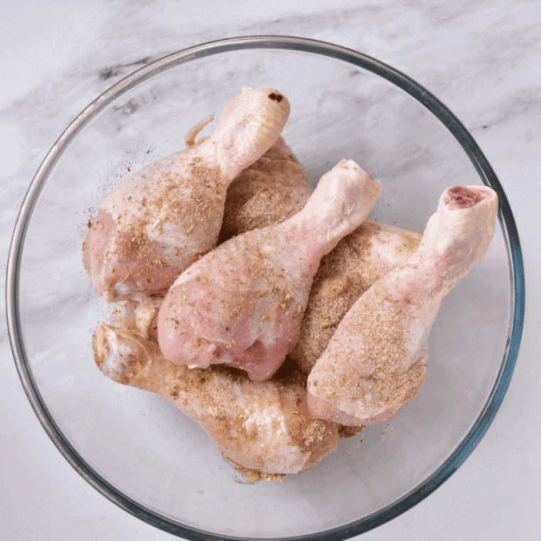 Chicken drumsticks and diced vegetables tossed in olive oil and seasonings, ready for air frying.