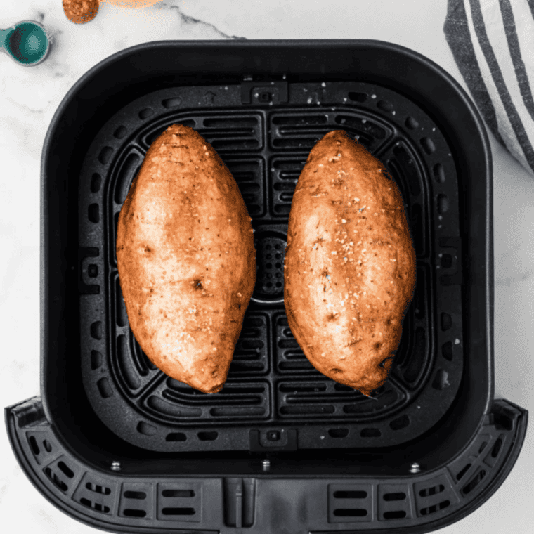 Four sweet potatoes arranged in a single layer with space between them in an air fryer basket