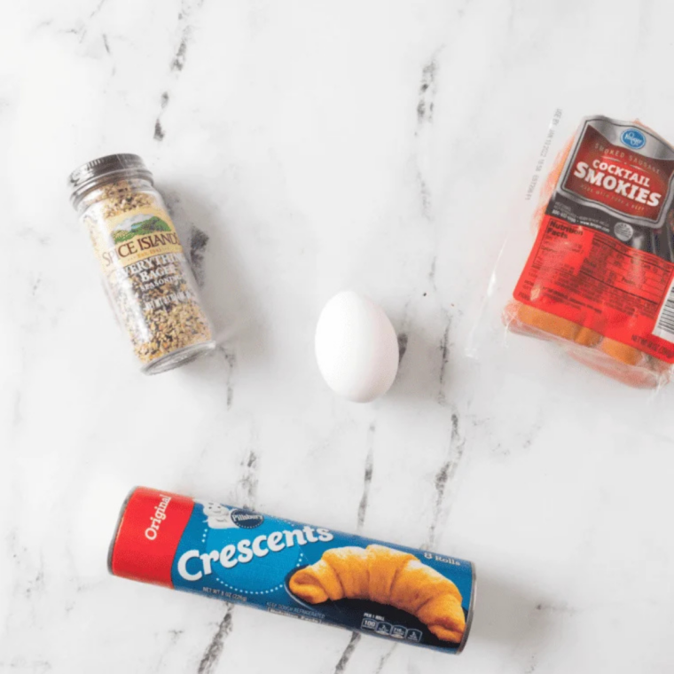 Ingredients for air fryer bagel dogs: hot dogs, crescent dough, egg, and sesame seeds