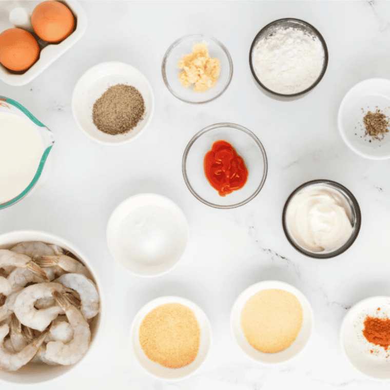 Raw shrimp, panko breadcrumbs, flour, eggs, and spices measured out for panko fried shrimp.