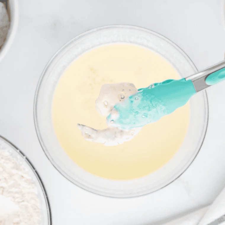 Breading station with three dishes of seasoned flour, beaten eggs, and panko breadcrumbs