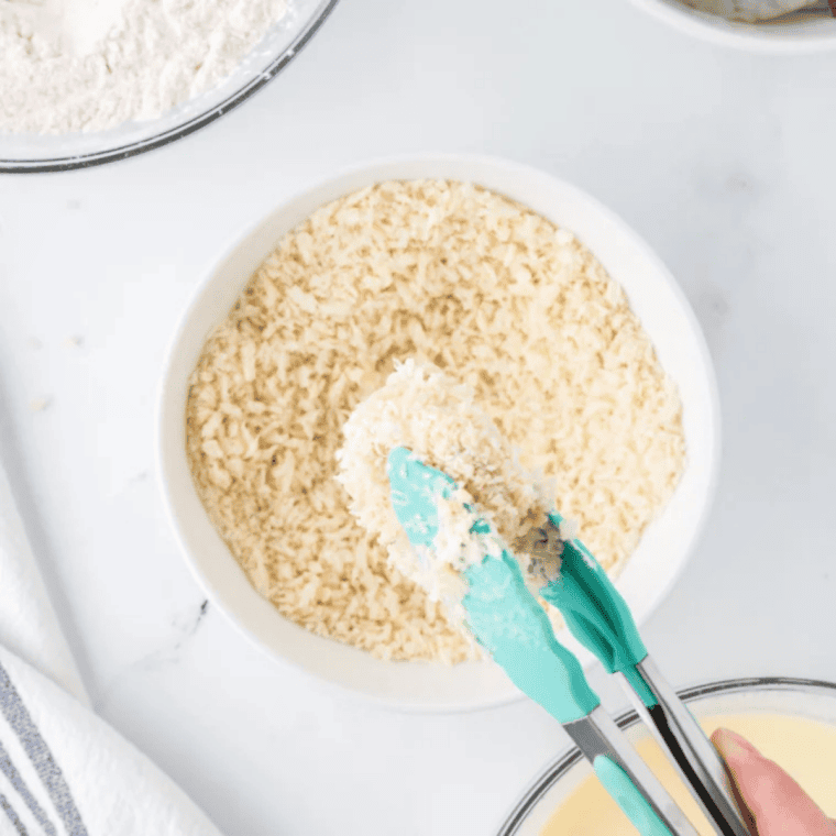 Breaded panko shrimp arranged in a single layer in the air fryer basket and sprayed with olive oil