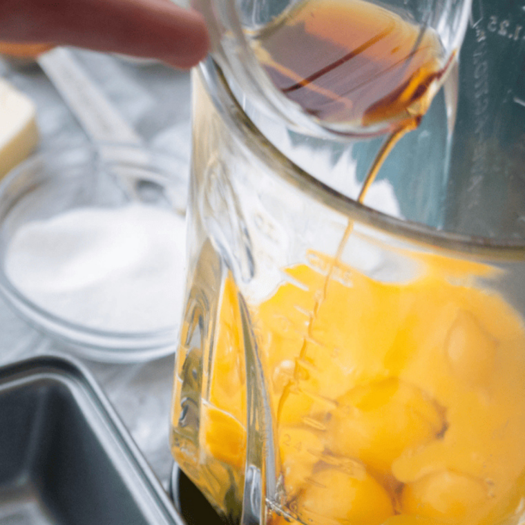 Mixing bowl with eggs, cream cheese, butter, cinnamon, vanilla, and coconut flour being whisked together.