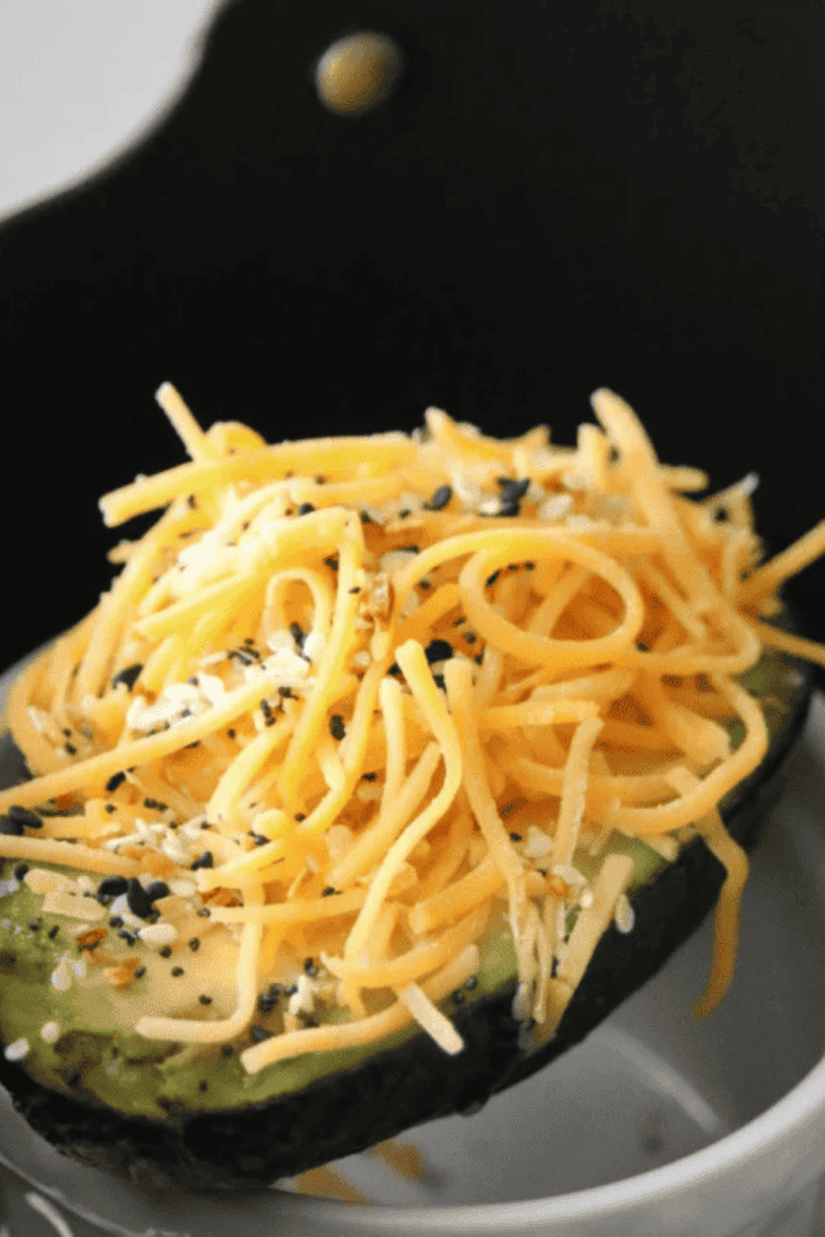 Perfectly cooked Air Fryer Stuffed Avocado served on a plate, garnished with herbs and a squeeze of lime.