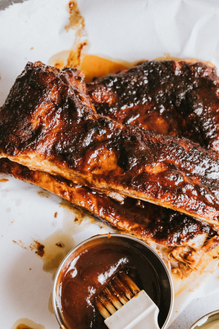 BBQ ribs cooking on a Ninja Foodi Grill, glazed with sauce and finished until caramelized with optional Ninja Woodfire smoky flavor method