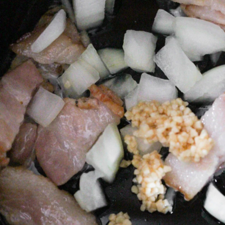 Ground turkey browning with diced onion in a stainless skillet before going into the slow cooker