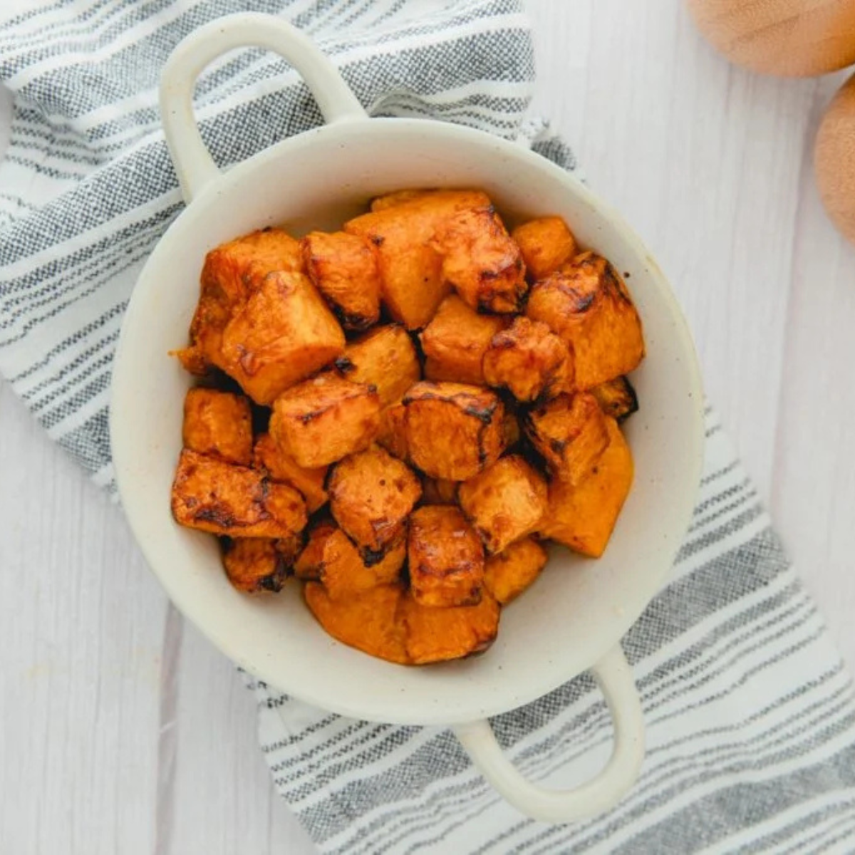 Freshly air fried frozen butternut squash cubes in the basket, browned at the edges and steaming