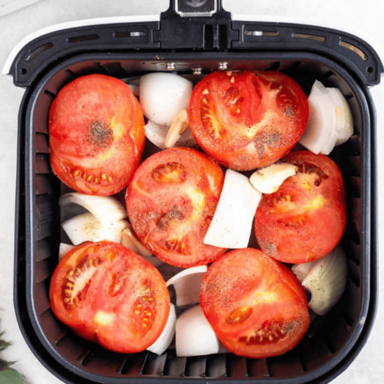 Halved Roma tomatoes on a cutting board, sliced lengthwise for air frying