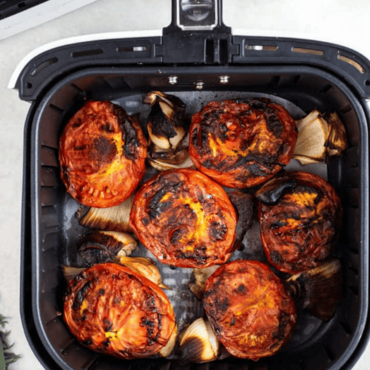 Seasoned Roma tomato halves arranged cut-side up in a single layer in an air fryer basket