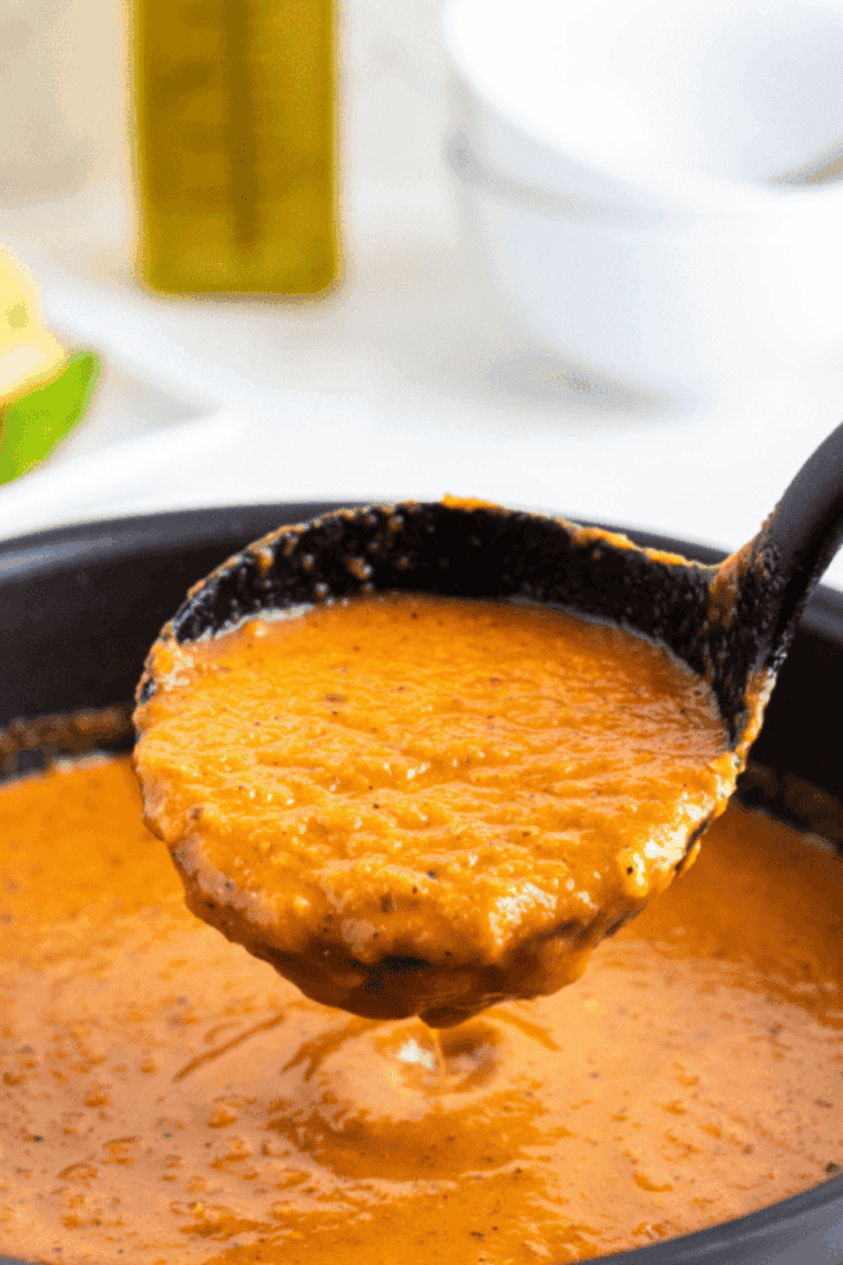 Bowl of smooth and creamy tomato soup made in the air fryer, garnished with fresh herbs.