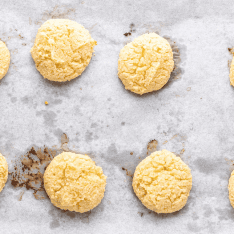 Keto cream cheese cookies baking in the air fryer, turning golden brown on the edges.
