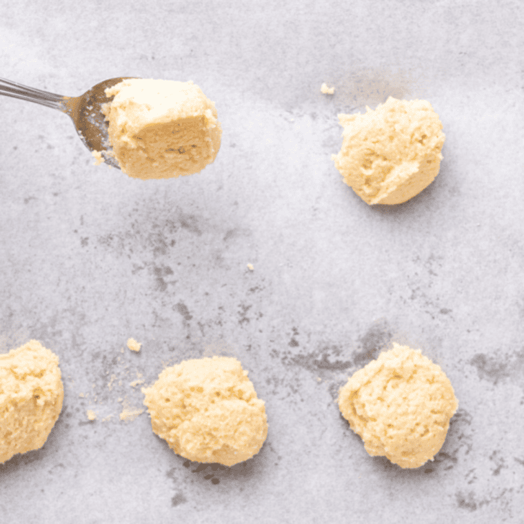 Keto cookie dough balls spaced in a parchment-lined air fryer basket ready to bake.
