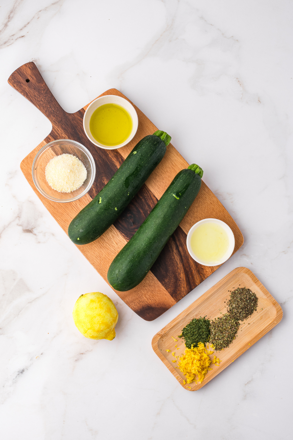 Sliced zucchini tossed with oil and seasoning in bowl before cooking on hot Blackstone griddle for even coating