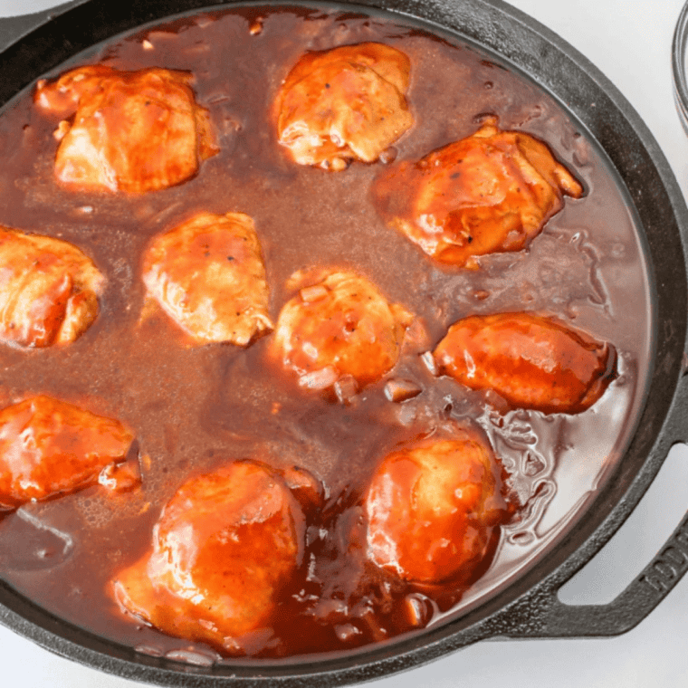 Chicken thighs in a bowl coated with peach glaze, marinating to soak in flavors.