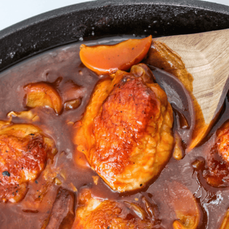 Marinated chicken thighs arranged skin-side down in air fryer basket, cooking until golden and fully cooked.